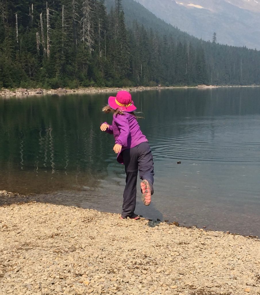 Young girl skipping a stone in a mountain lake.